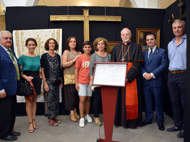 Celebración de un acto formal con un grupo de personas posando junto a un obispo y un diploma en un ambiente religioso.