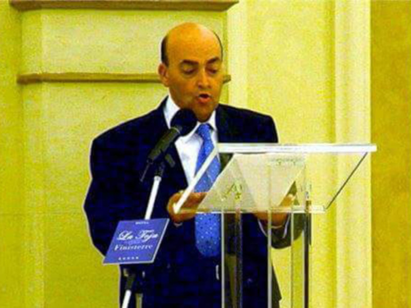 Hombre en traje hablando desde un podio en un evento formal.