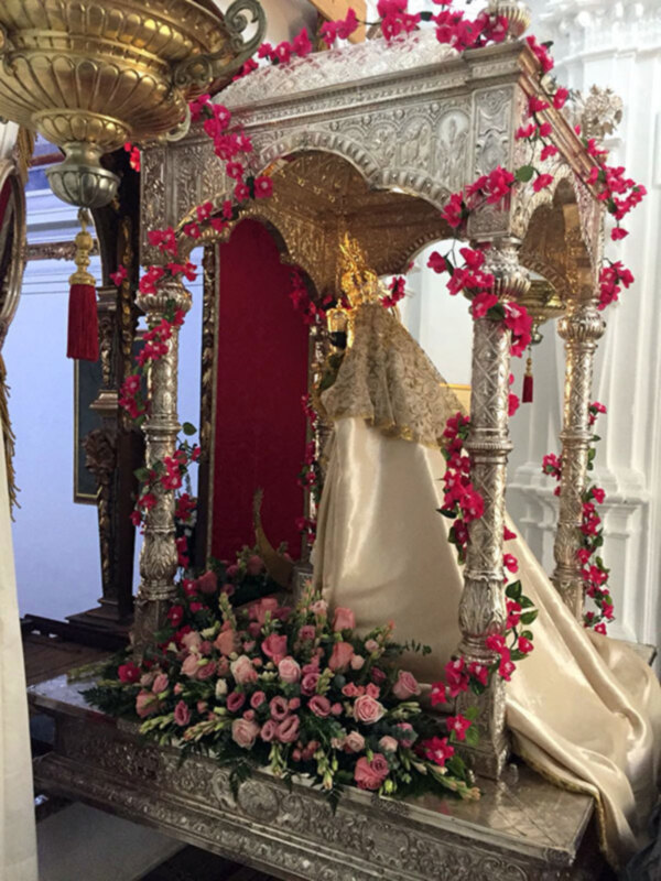 Altar con imagen de Virgen María adornada con flores y ornamentos dorados.