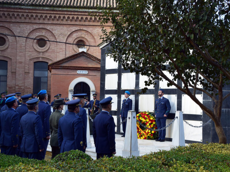 Un grupo de soldados en uniforme militar se reúne en un lugar ceremonial, frente a una estructura con un letrero y un círculo de flores. El ambiente es formal y respetuoso, indicando una ceremonia o evento importante.