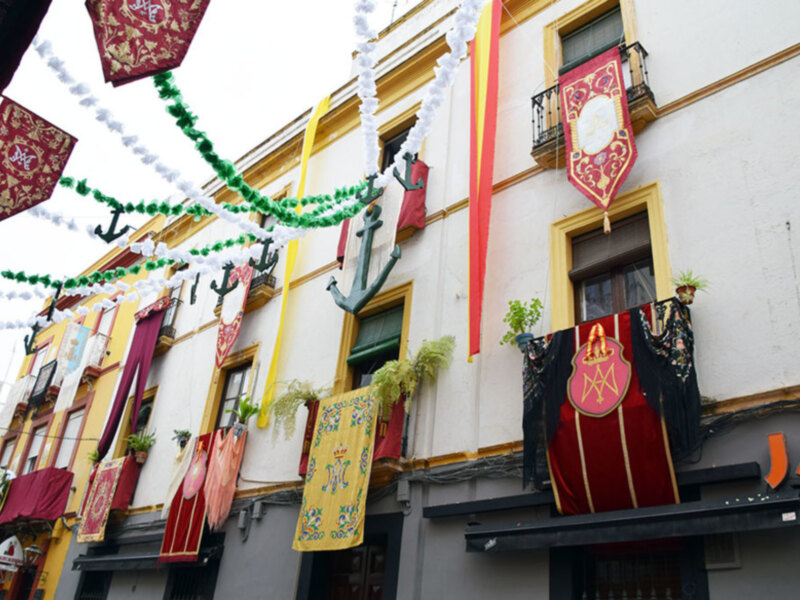 Fachada decorada con banderines y guirnaldas en una calle de España, probablemente durante una celebración o festividad.