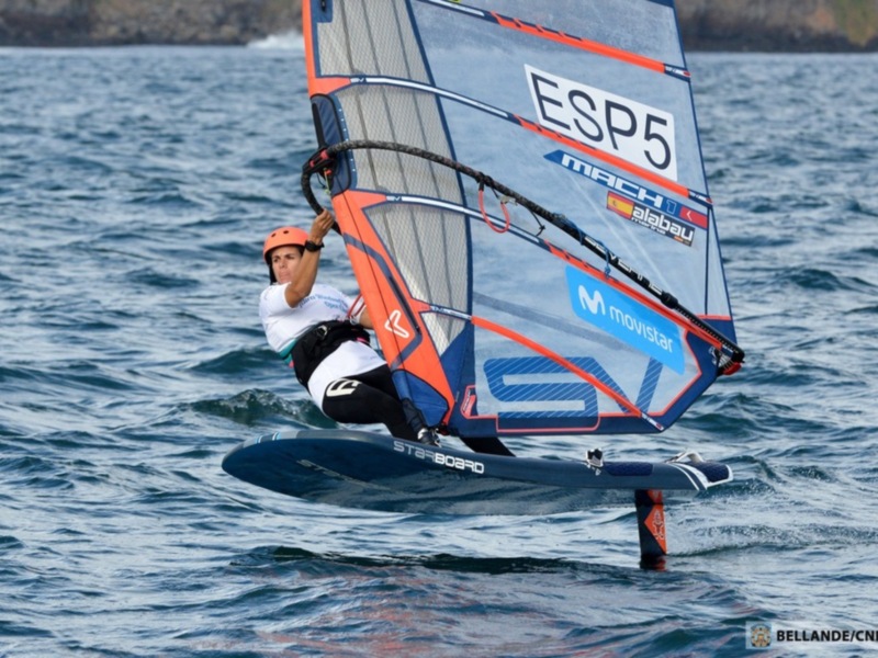 Competidor de windsurf en acción con vela 'ESP5' y 'Mach 1', navegando en el mar abierto.