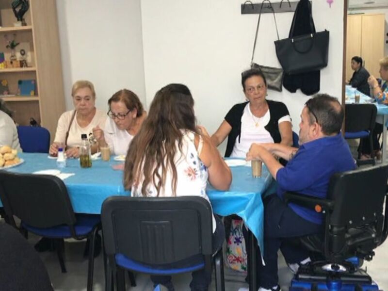 Reunión de personas en una mesa redonda, discutiendo y compartiendo en un ambiente acogedor.
