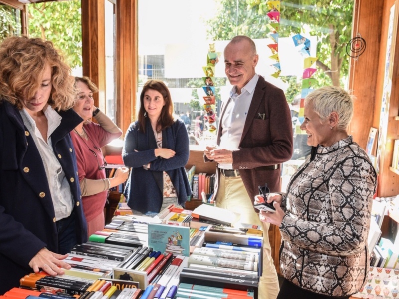 Personas intercambiando libros en una tienda de libros con un ambiente acogedor y soleado.