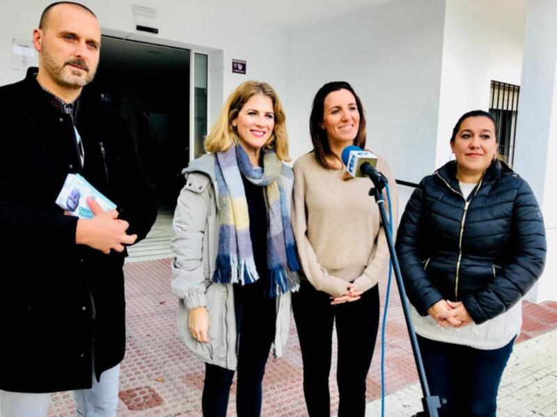 Tres personas posan frente a una entrada, con un micro en el centro.