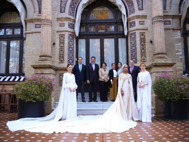 Una familia posa frente a una arquitectura histórica con plantas y sillas en el fondo.
