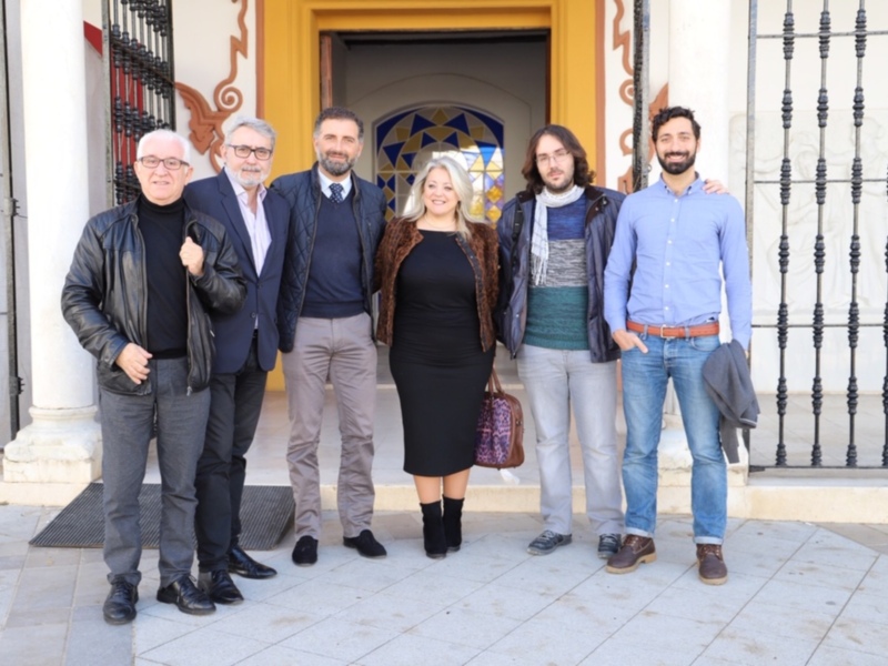 Grupo de personas posando juntos frente a una entrada decorativa con detalles arquitectónicos.