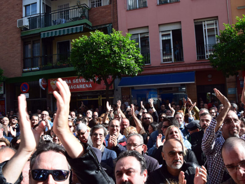 Celebración pública en una calle urbana con personas levantando las manos en señal de alegría o apoyo.