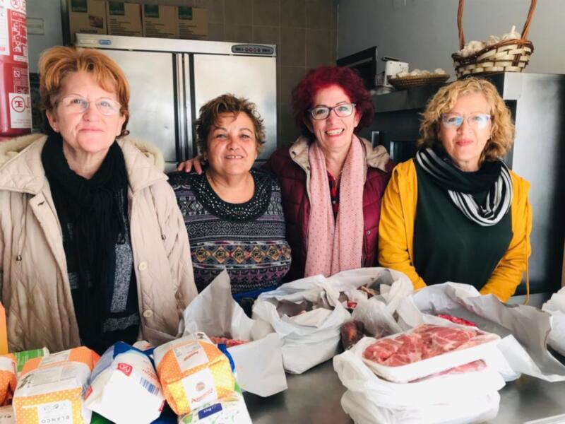 Voluntarios sonrientes con donaciones de alimentos en una cocina comunitaria.