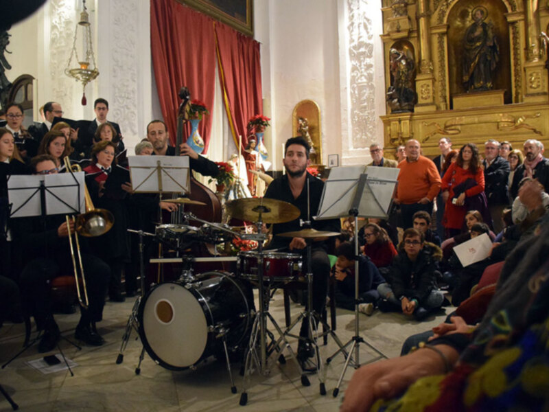 Concierto de música en una iglesia histórica con orquesta y público apreciando la actuación.