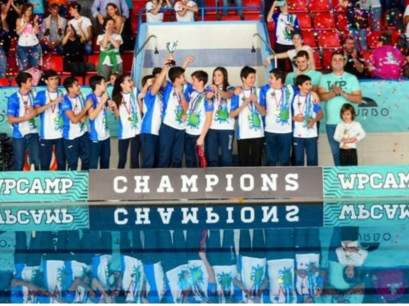 Equipo juvenil celebrando su victoria como campeón en un evento deportivo.