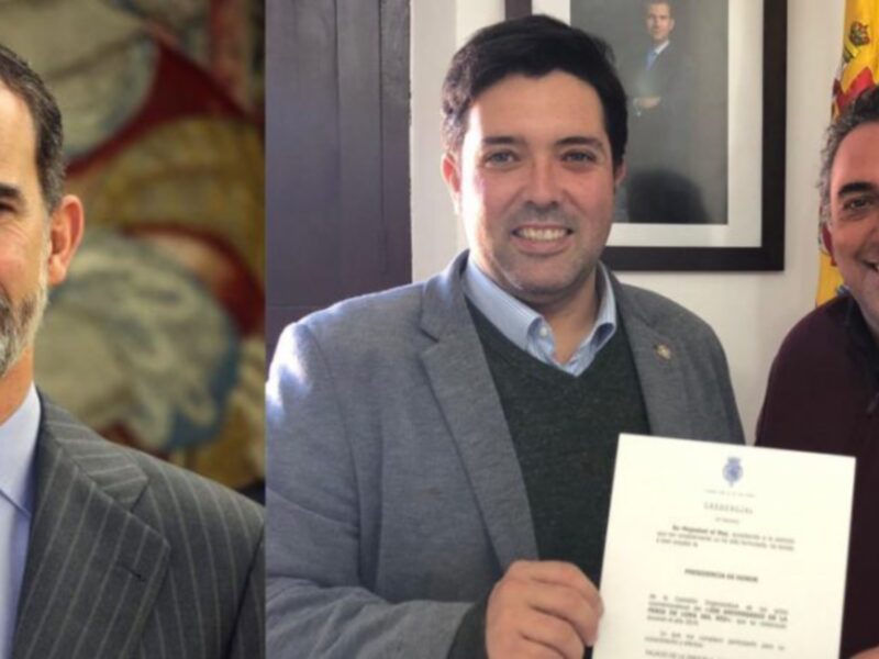 Reunión oficial entre dos hombres, uno en traje y otro con certificado, en un entorno formal con banderas y retratos.