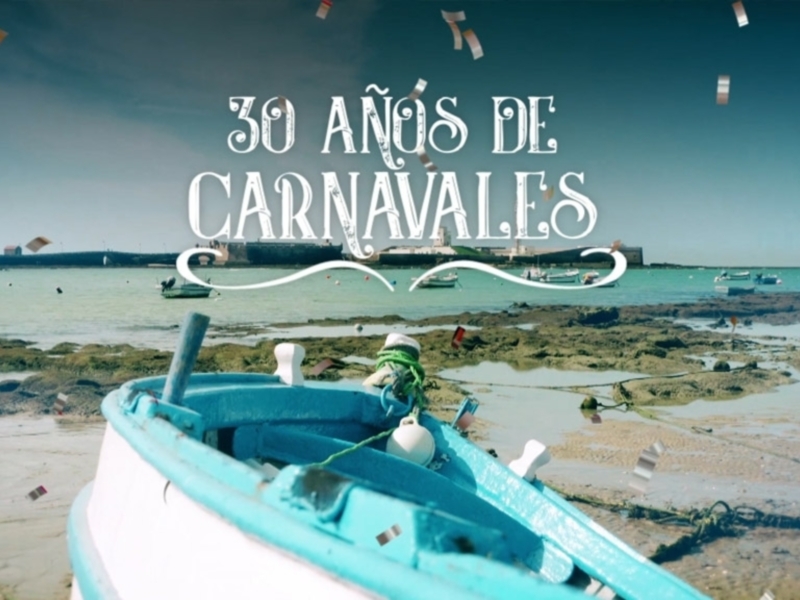Celebración de 30 años de Carnaval en una costa tranquila con barcos y confeti flotante.