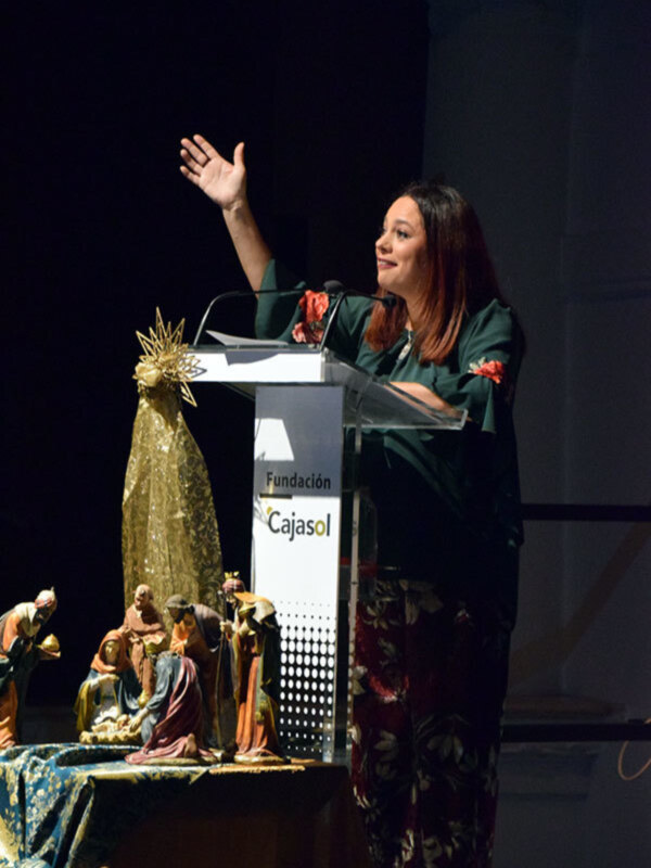 Mujer hablando en un evento en la Fundación Cajasol, con una representación de la natividad en el fondo.