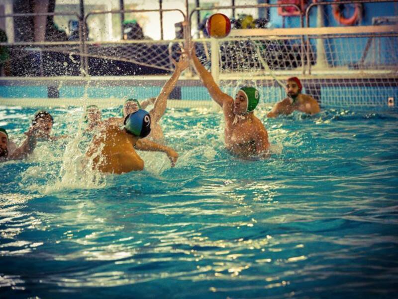 Un emocionante partido de waterpolo en una piscina de agua azul, con jugadores en acción y una pelota en movimiento.