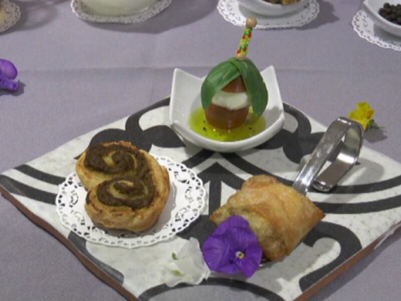 Plato de postres artísticos con pastel de espiral, frutas y decoración floral.