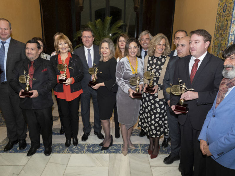 Grupo de personas celebrando con trofeos en un evento formal.