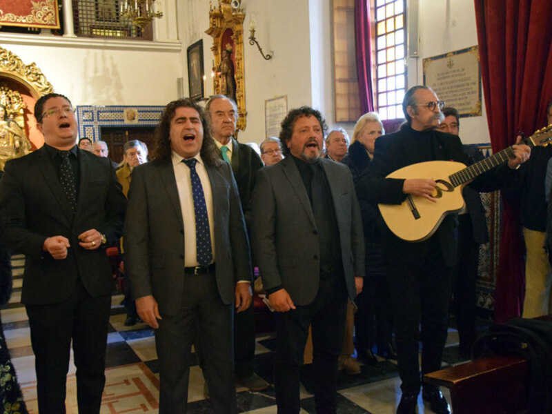 Concierto coral en iglesia, cantantes y músico tocando guitarra.