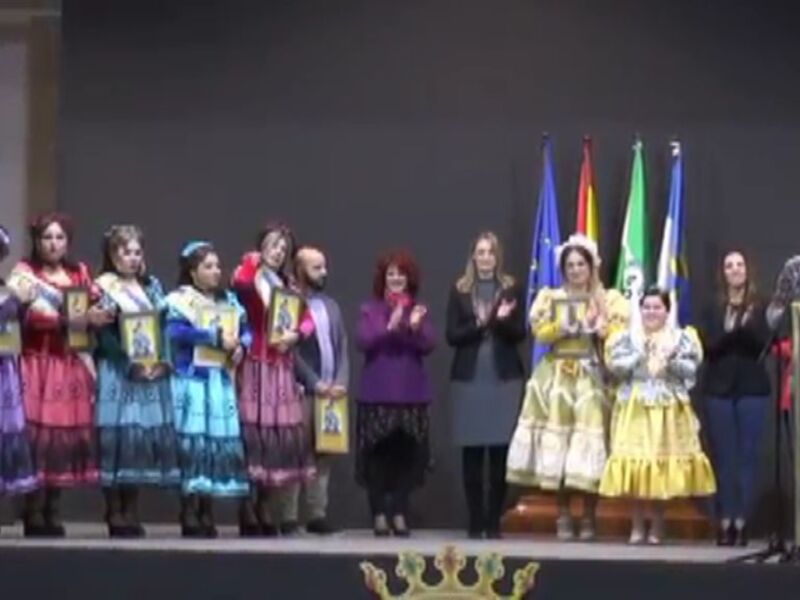 Gala de reconocimiento con vestimenta tradicional y banderas en un escenario.