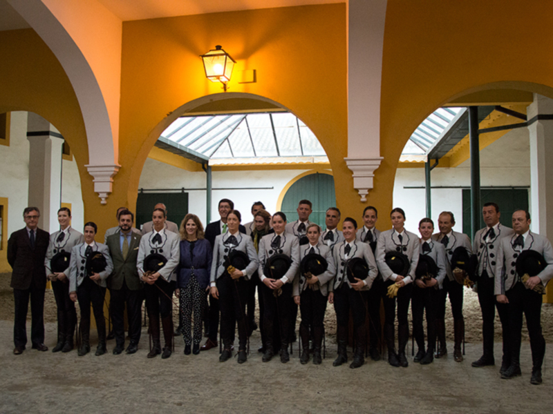 Gruppo di persone in abiti tradizionali posano in un ambiente architettonico con arcate e luci accese.