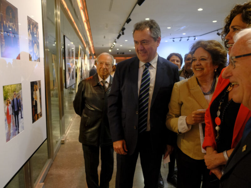 Visita de autoridades a una exposición fotográfica en un recinto bien iluminado.