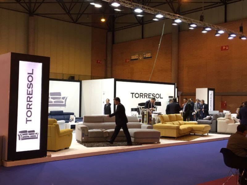 Salón de exposición con muebles de sala de estar y un hombre caminando por el centro.