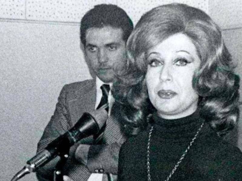 Una imagen histórica de una mujer hablando en un micrófono, posiblemente en un evento formal o de comunicaciones.