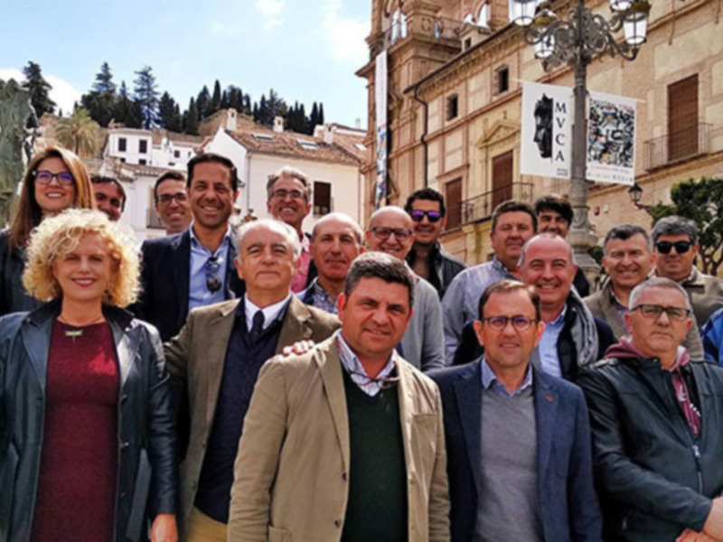 Grup de persones en una foto de família davant d'edificis històrics a una localitat espanyola.