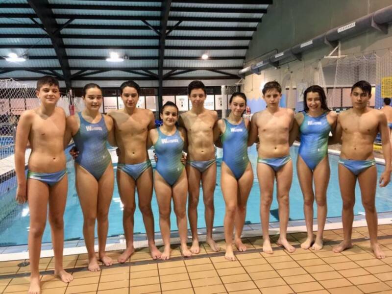 Equipo de natación juvenil posando junto a la piscina.
