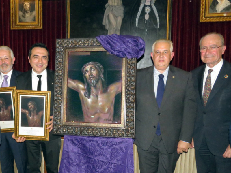 Tres hombres en trajes posan junto a dos imágenes de Cristo, una de las cuales está enmarcada y cubierta con un pañuelo púrpura. La escena se desarrolla en un fondo de cortinas rojas y un lienzo con una imagen de una persona vestida con un manto.