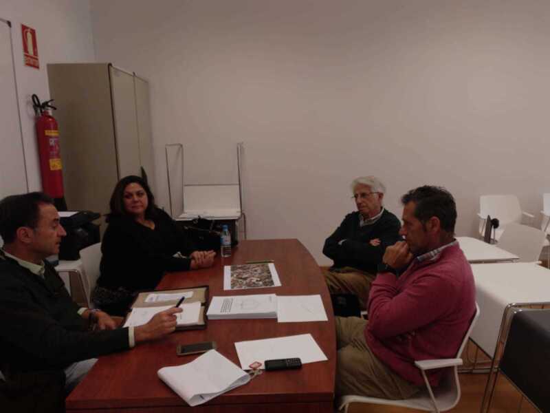 Reunión de trabajo en una sala de reuniones con documentos y un extintor en el fondo.