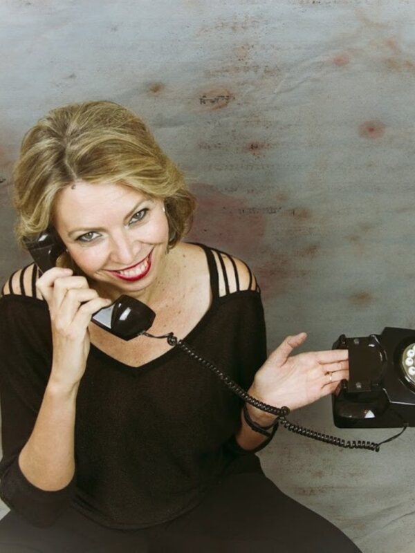 Retrato de mujer hablando por teléfono antiguo, sonriendo con confianza.