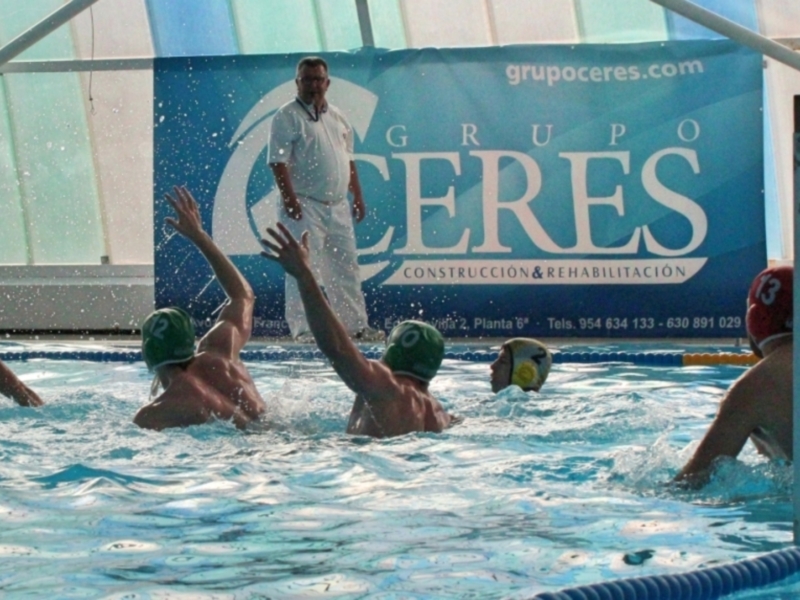 Jugadores de waterpolo en acción durante un partido en una piscina cubierta.