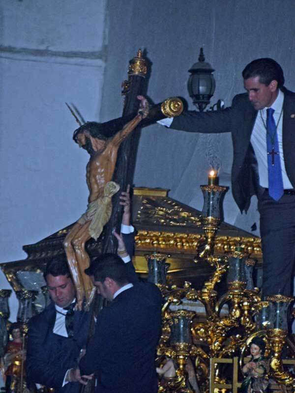 Cristo crucificado en procesión nocturna en una iglesia.