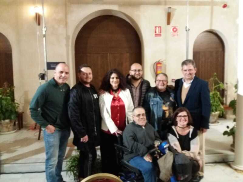 Una imagen de un grupo de personas posando juntos en una sala con arcos y plantas.