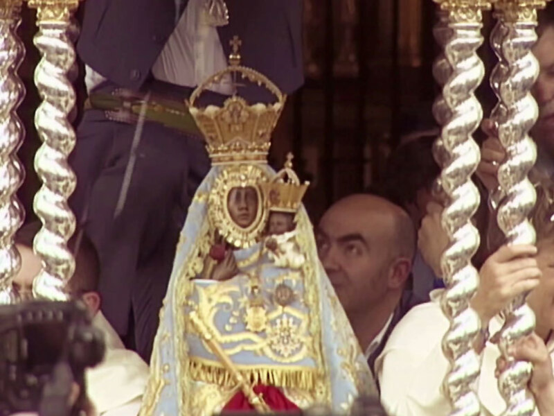 Procesión religiosa con imagen de la Virgen María en un manto ornado y portada por devotos.