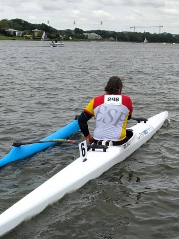 Competidor en canoa durante una regata en aguas abiertas, con el número 246 y la bandera de España.