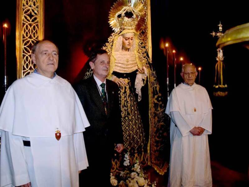 Celebración religiosa con la imagen de una Virgen y sacerdotes en una procesión nocturna.