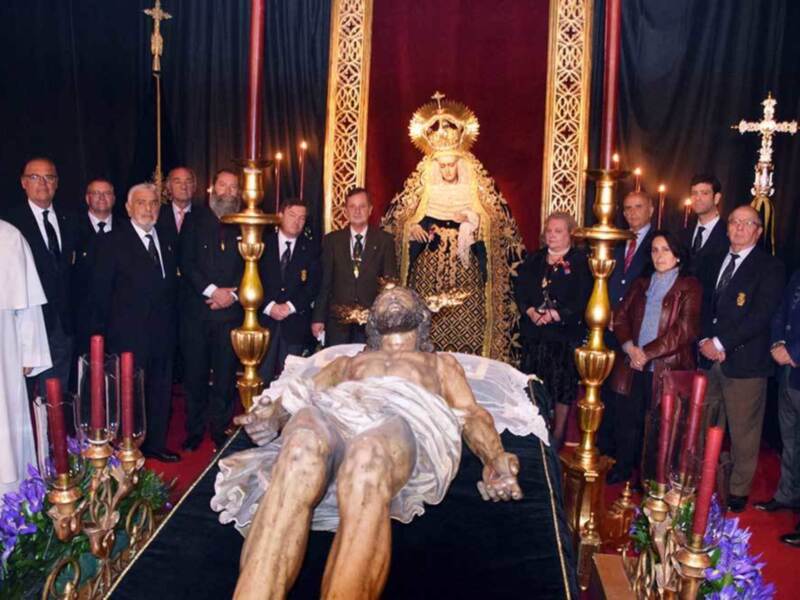 Cristo de la Buena Muerte en procesión, rodeado por autoridades y devotos en una ceremonia religiosa.