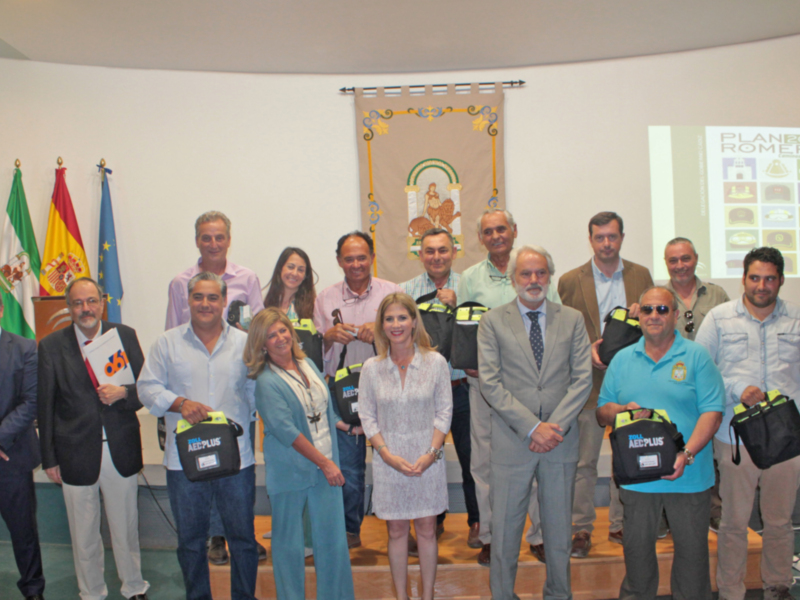 Presentación del Plan 2019 en una reunión oficial con participantes sosteniendo bolsas de AED Plus.
