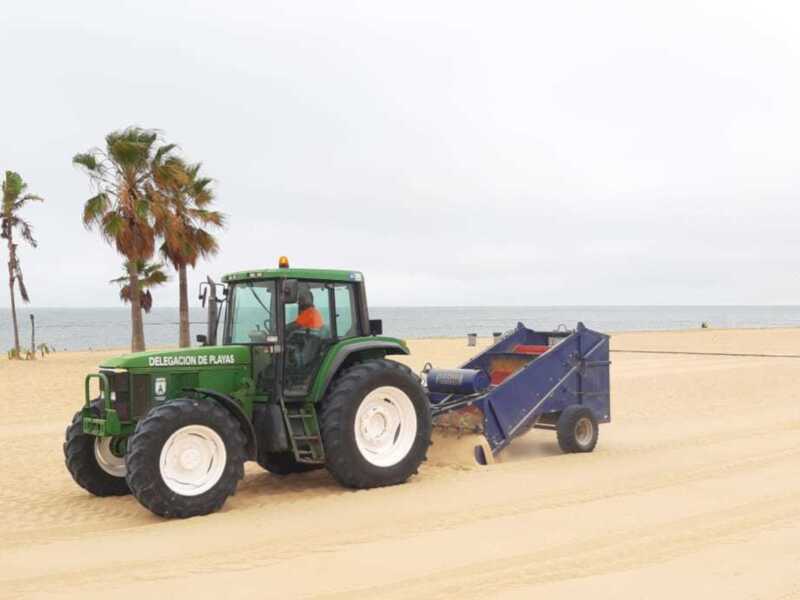 Tractor limpiando la playa con maquinaria de limpieza.