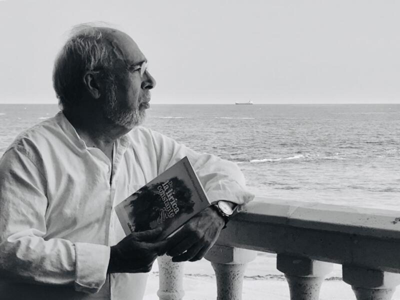 Hombre leyendo un libro sobre la orilla del mar.