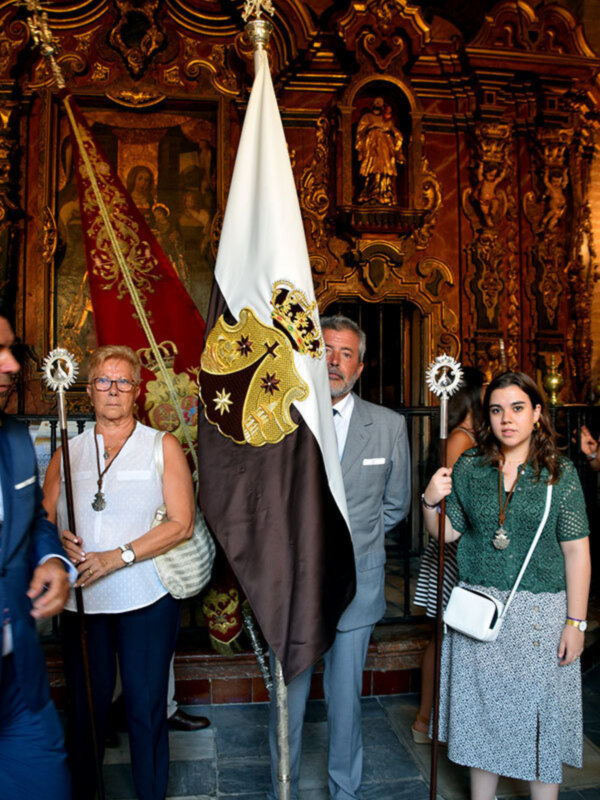 Personajes con estandartes y ornamentos religiosos en un interior barroco.