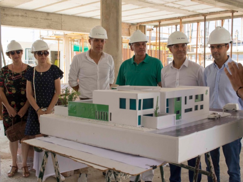Grupo de personas revisando un modelo arquitectónico en un sitio de construcción en proceso.