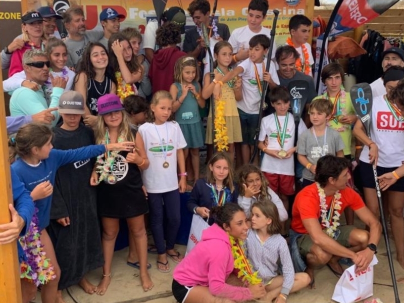 Equipo de surf con medallas y leis en una celebración en Discover Huella Festival de la Costeña.
