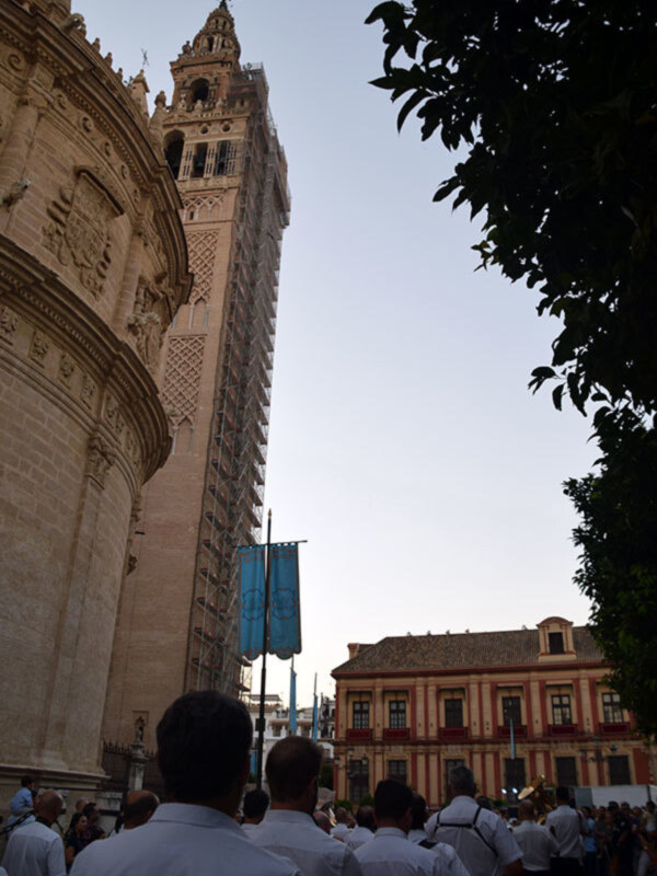 Catedral de Sevilla con la Giralda en primer plano y una procesión en la plaza de la Virgen del Pilar en segundo plano.