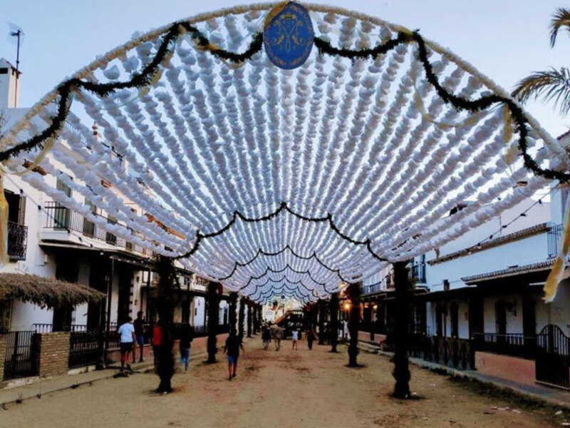 Feria de las Flores en Córdoba, España, con arco decorado con flores blancas y rojas, iluminado por la tarde.