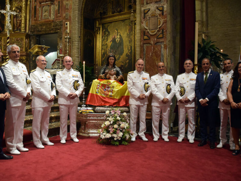 Celebración religiosa con uniformes militares y bandera española en un interior de iglesia.