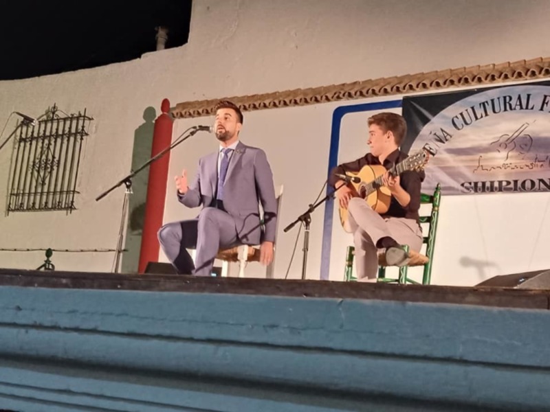 Cantante y guitarrista en escenario durante un evento cultural.