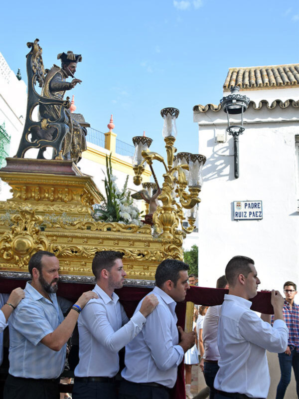 Hombres llevando una estatua de oro en una procesión religiosa en España.